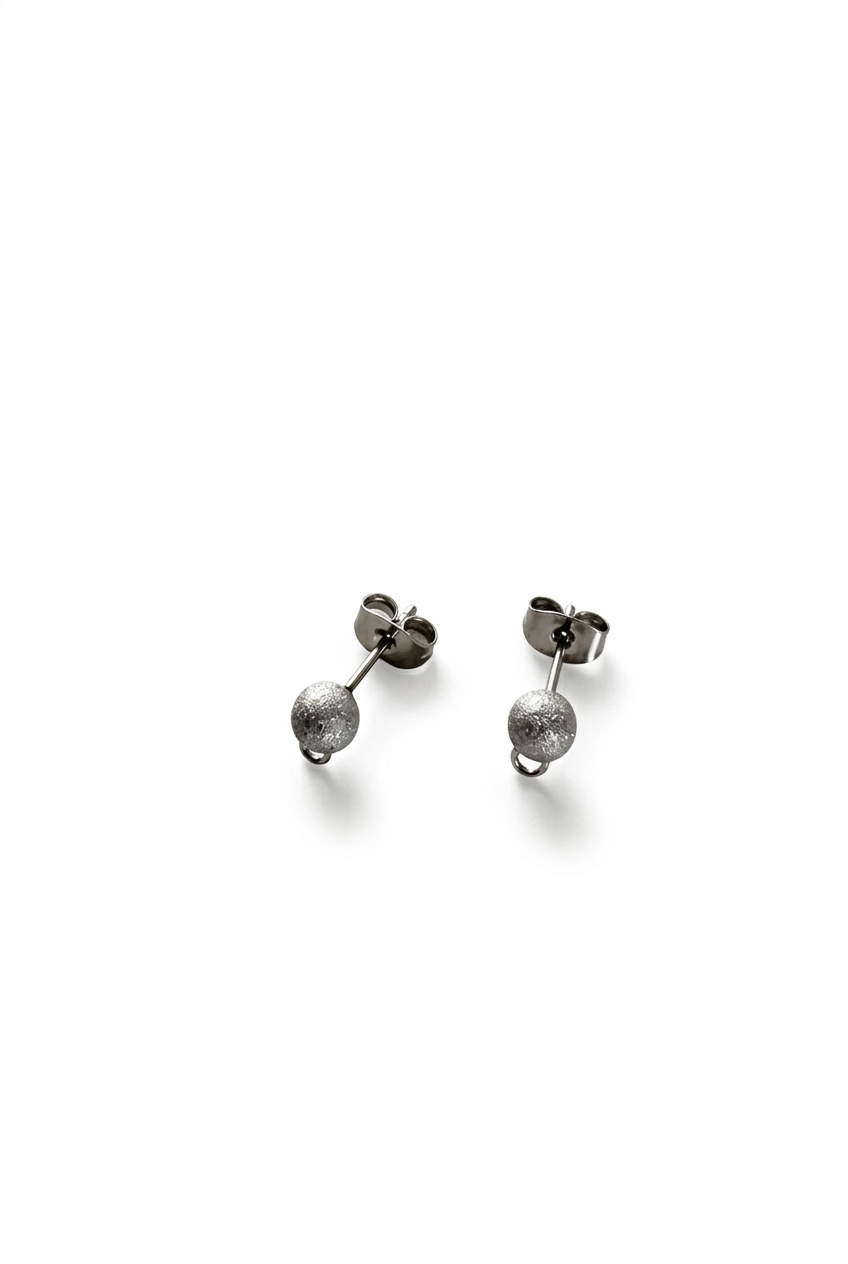 Clous d’oreilles boules argentés sur fond blanc