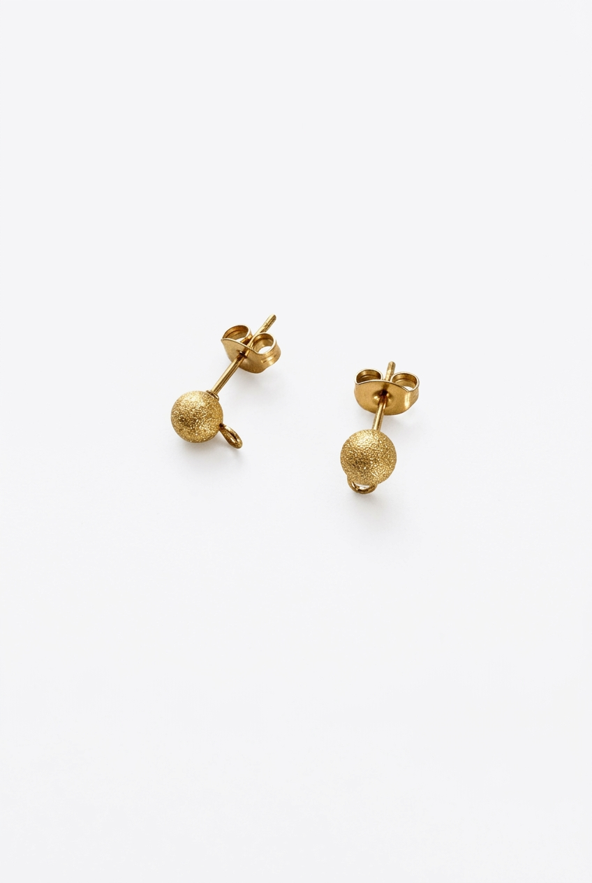 Clous d’oreilles boules dorés sur fond blanc